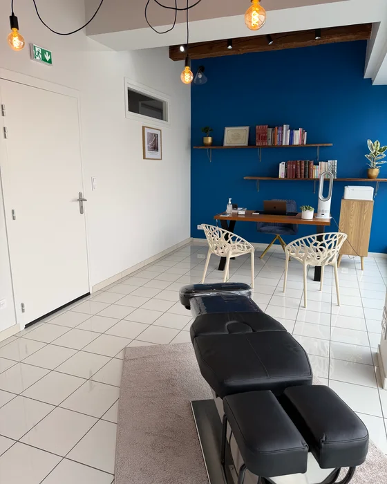La salle du cabinet : la table au premier plan, le bureau devant le mur bleu.